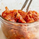 tossing cubed chicken thighs with olive oil and spices in a bowl.