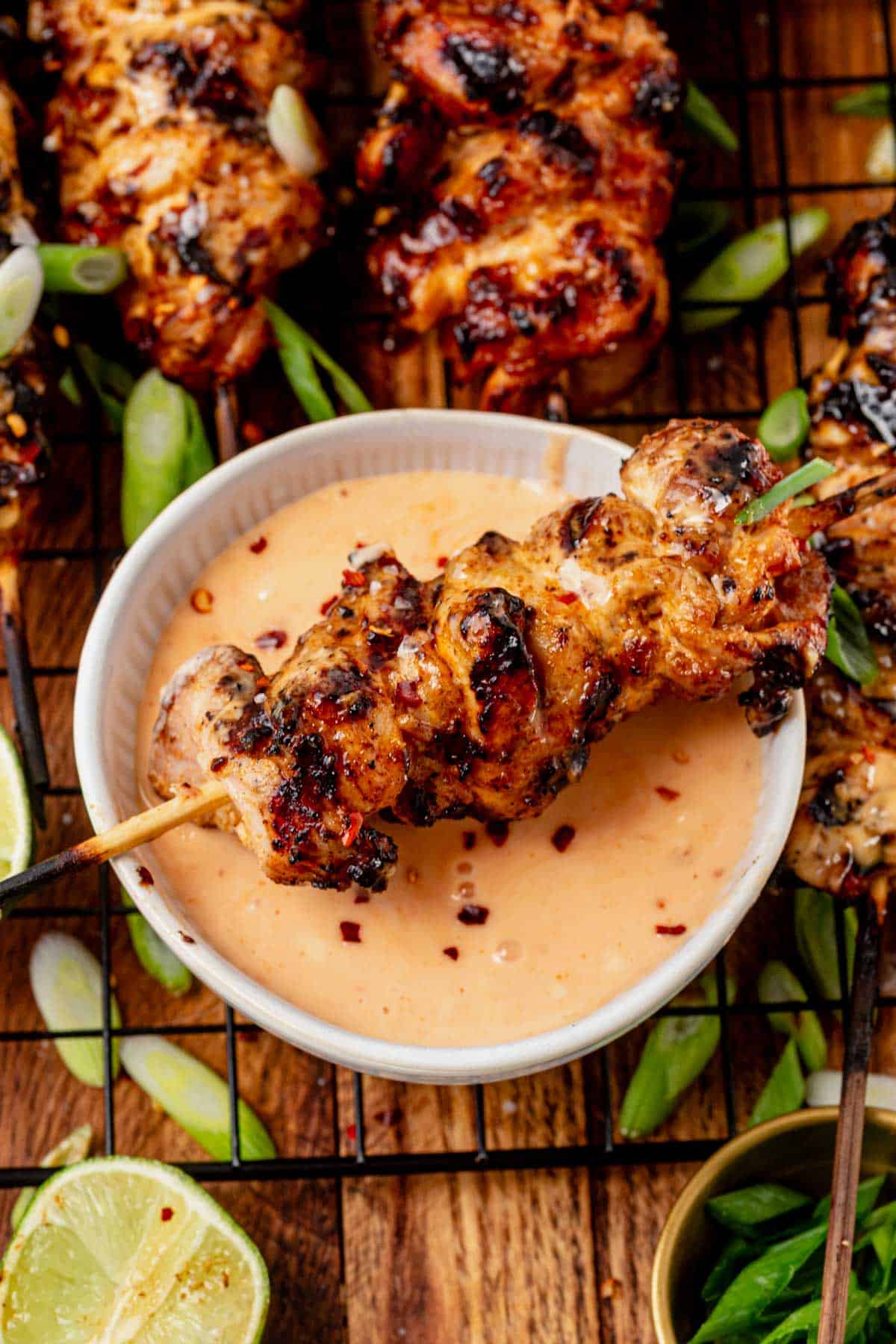 dipping a grilled bang bang chicken skewer into a bowl of bang bang sauce.