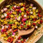 a wooden bowl of grilled pineapple salsa with a wood serving spoon.