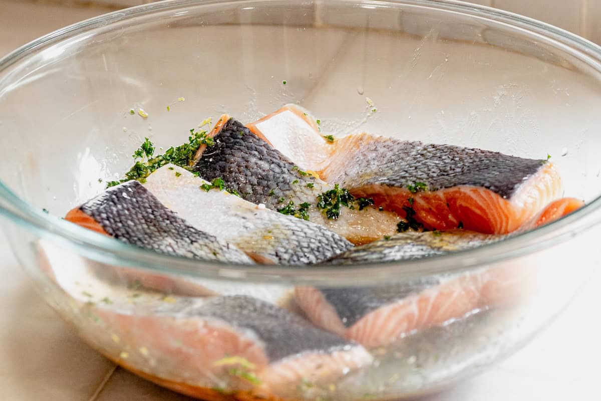 salmon fillets marinating in a lemon herb marinade.