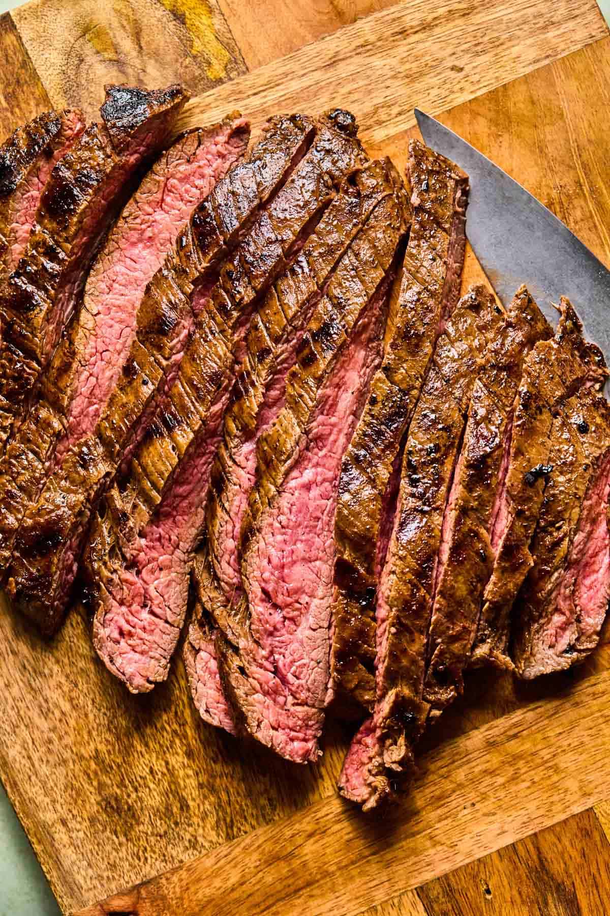 grilled flank steak sliced on a cutting board