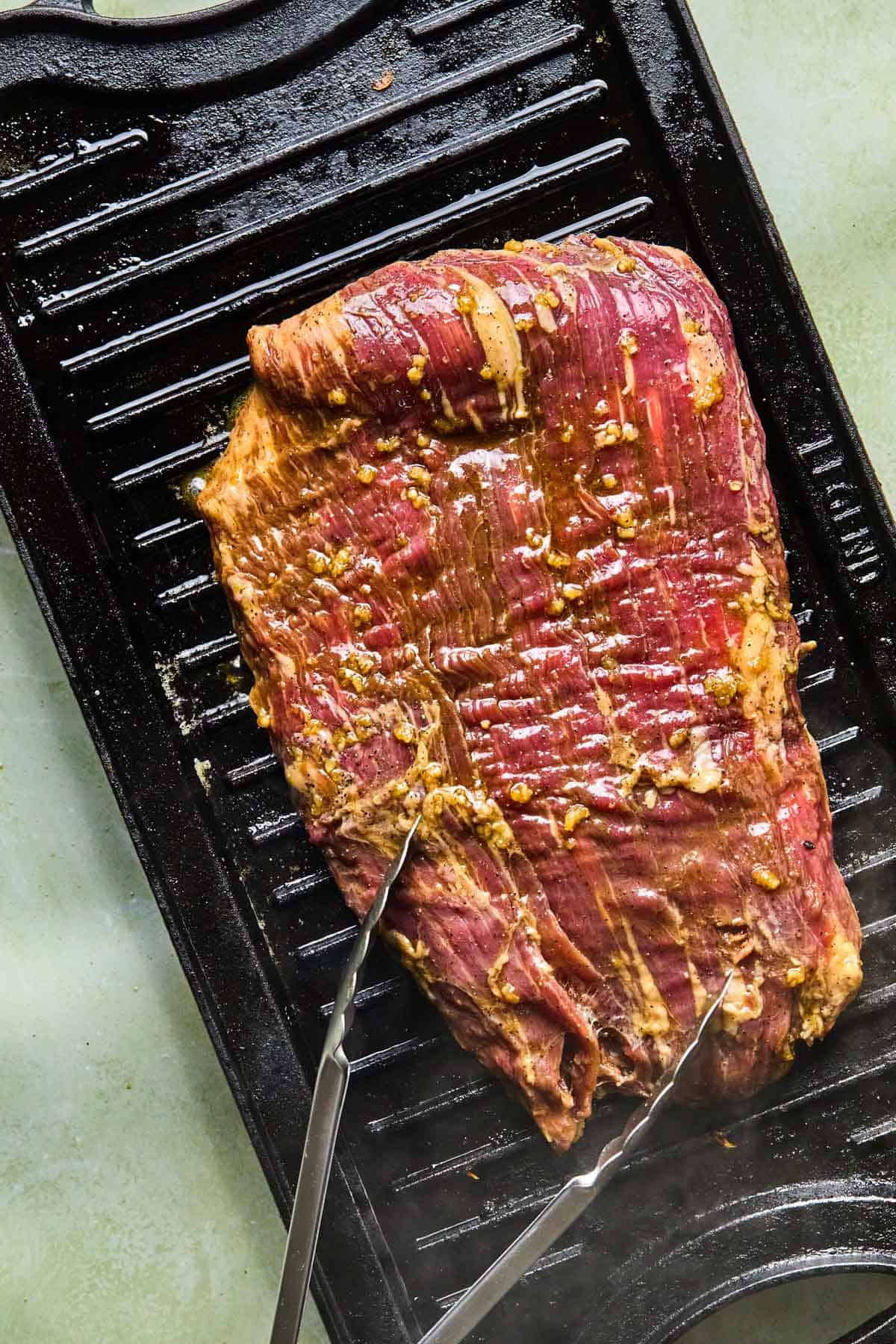 marinated flank steak placed on the grill