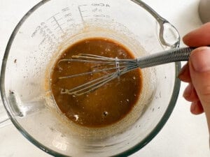 whisking pad thai sauce in a bowl.