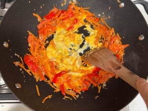 scrambling eggs in a wok with pad thai vegetables.