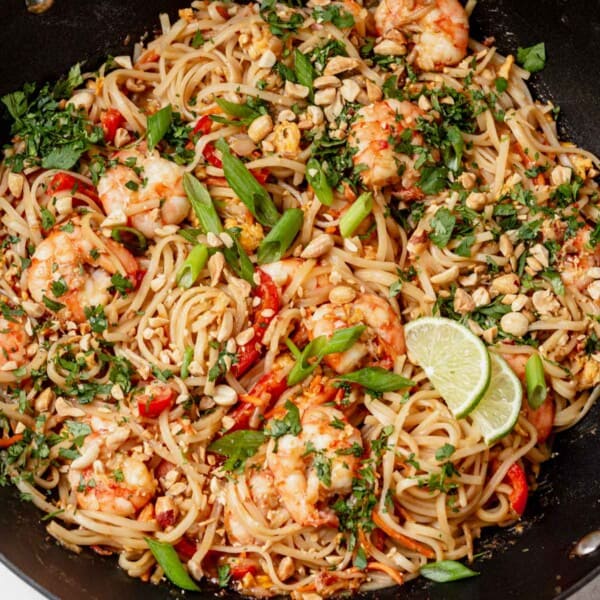 pad thai in a wok with green onions and cilantro.