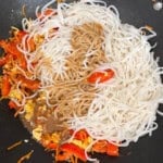 pad thai sauce and cooked noodles in a wok with pad thai vegetables.