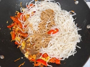 pad thai sauce and cooked noodles in a wok with pad thai vegetables.