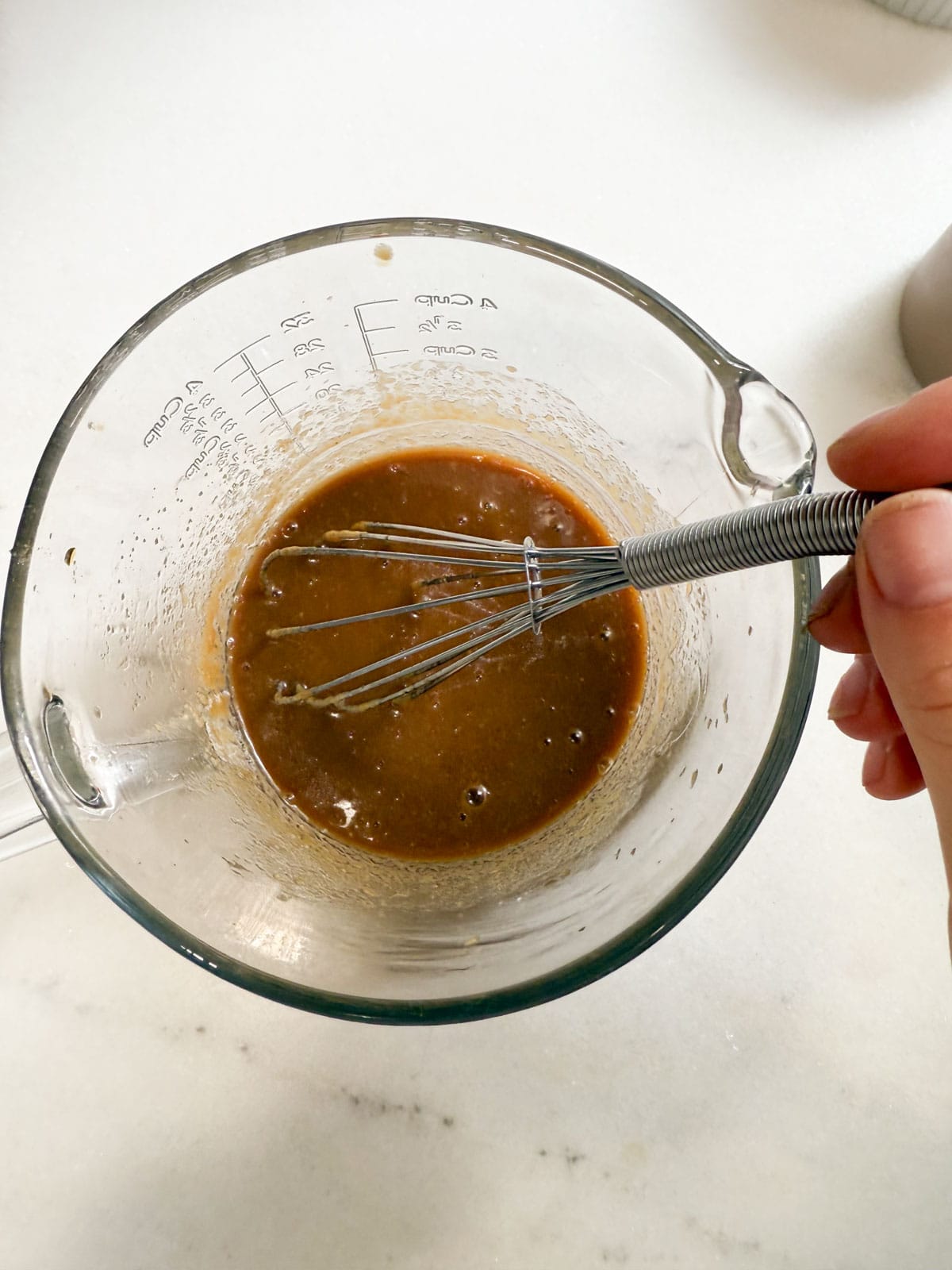 whisking pad thai sauce in a bowl.