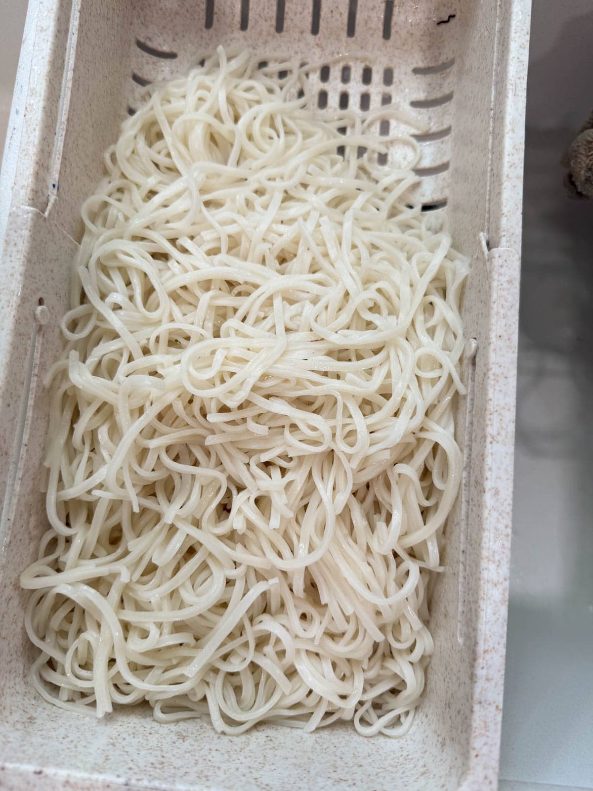 pad thai noodles draining in a collander.
