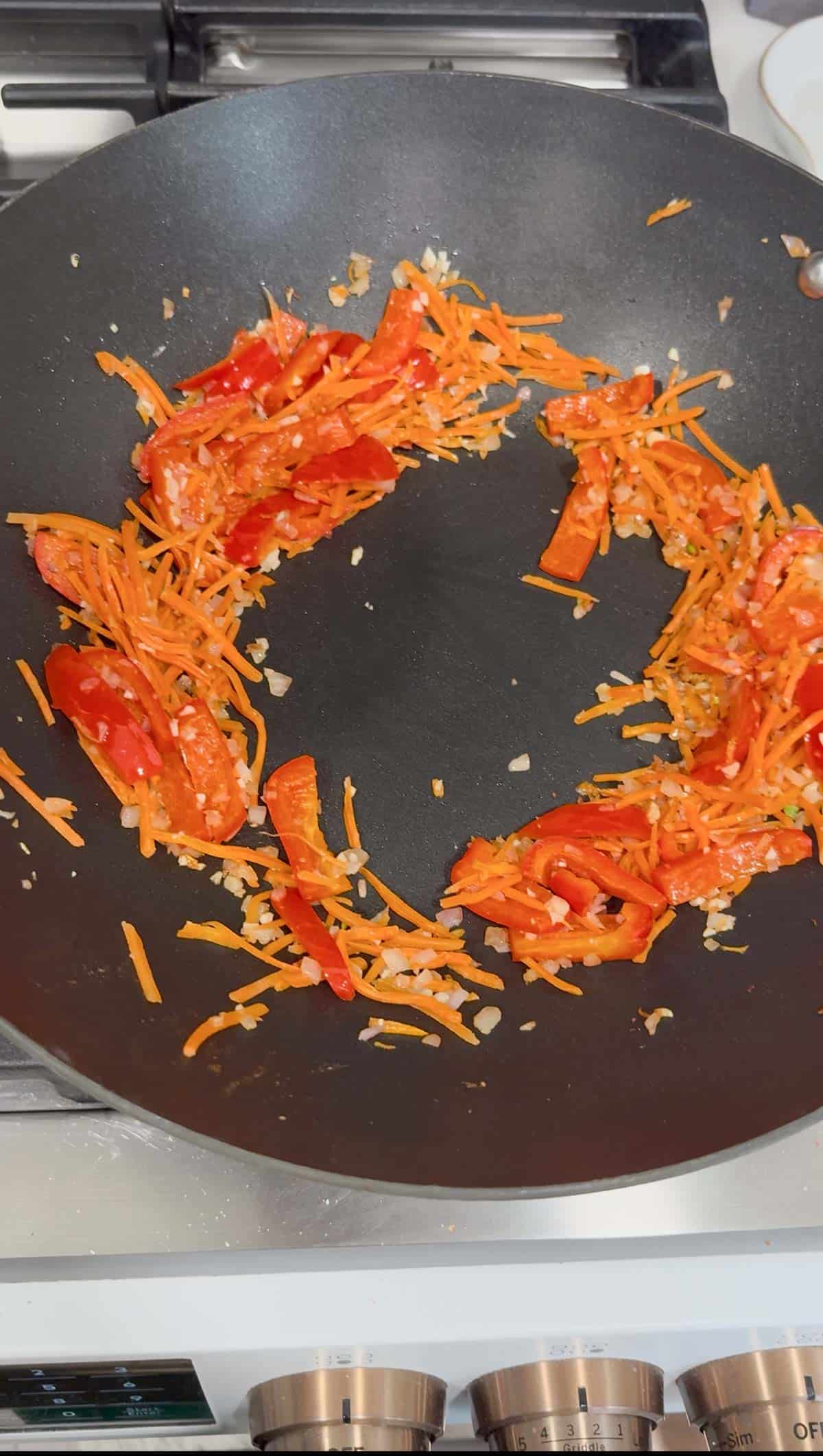 cooking bell pepper and carrots in a wok.