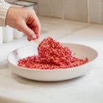 coating a strawberry ice cream bar in a cookie strawbery coating in a plate.