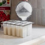 Pouring a vanilla ice cream base into popsicle molds.
