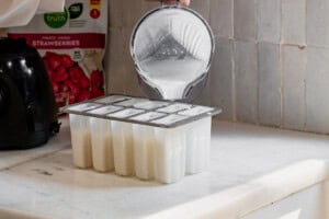 Pouring a vanilla ice cream base into popsicle molds.