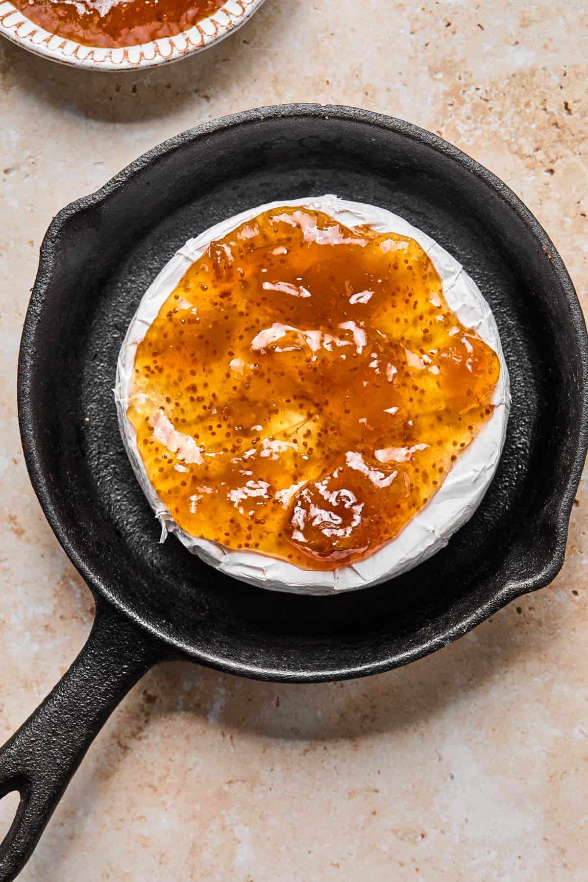 wheel of brie in a mini cast iron with fig jam spread on top