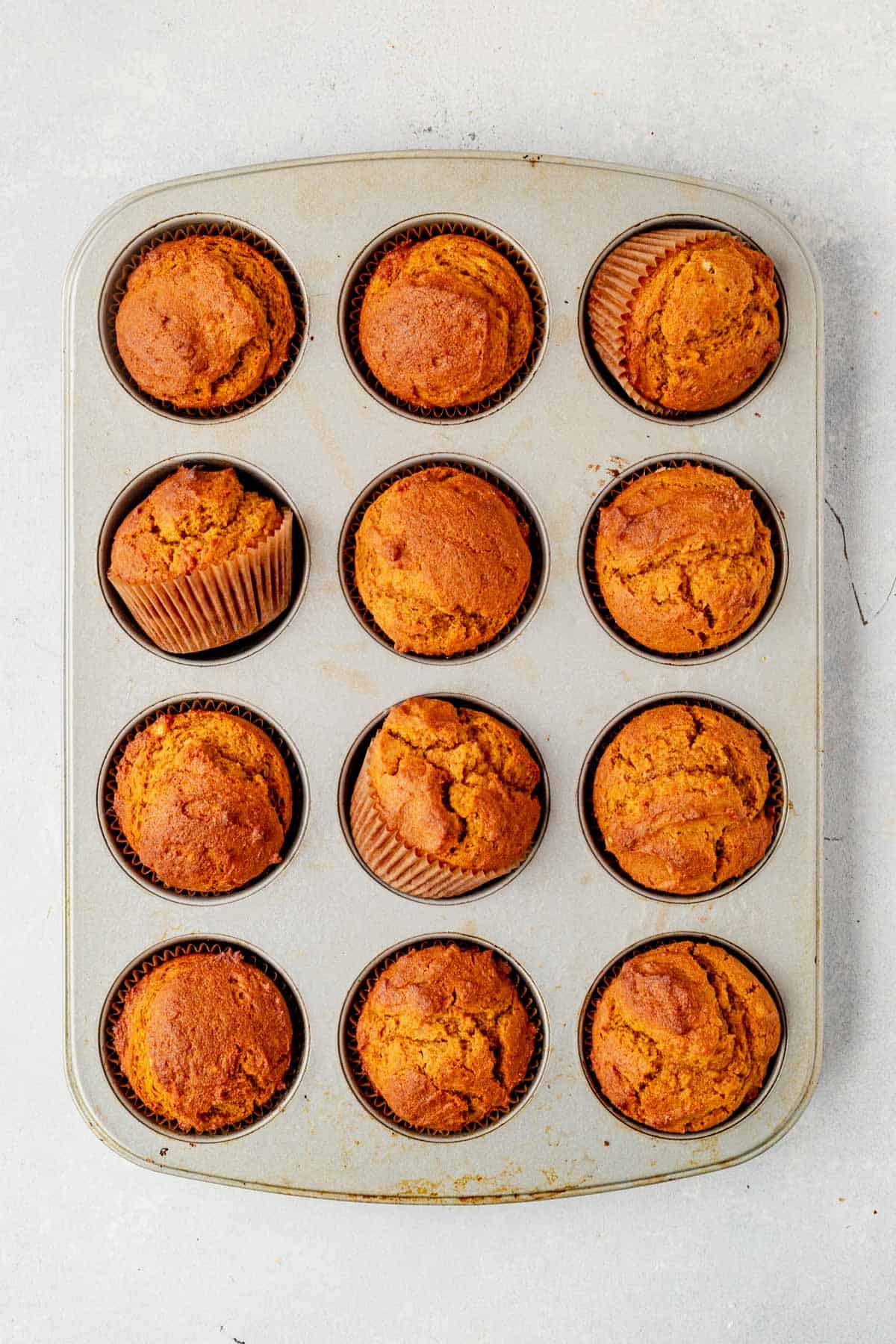 gluten free pumpkin muffins baked and cooling in a muffin tin on the counter.