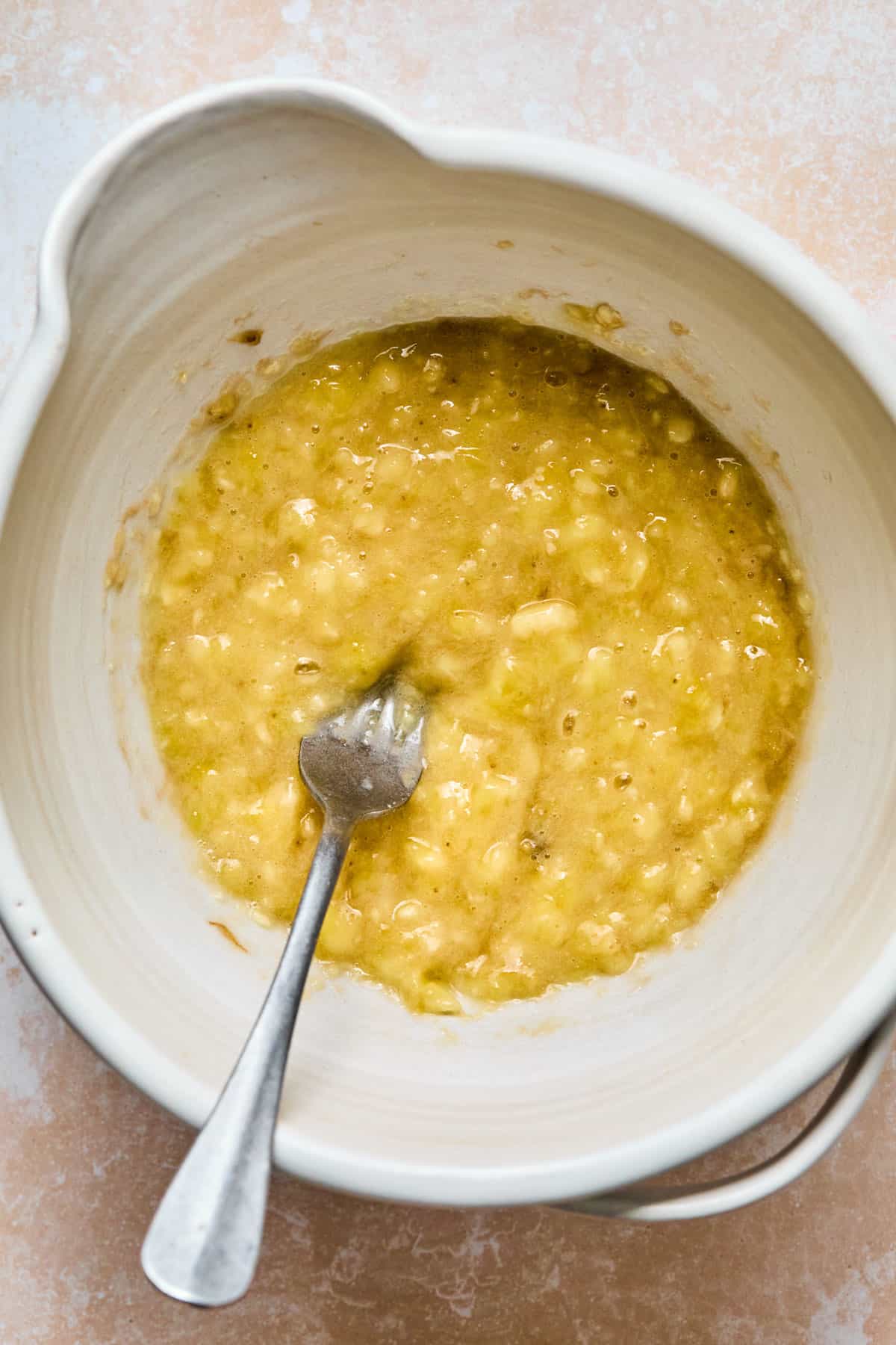 ripe bananas mashed with a fork in a mixing bowl