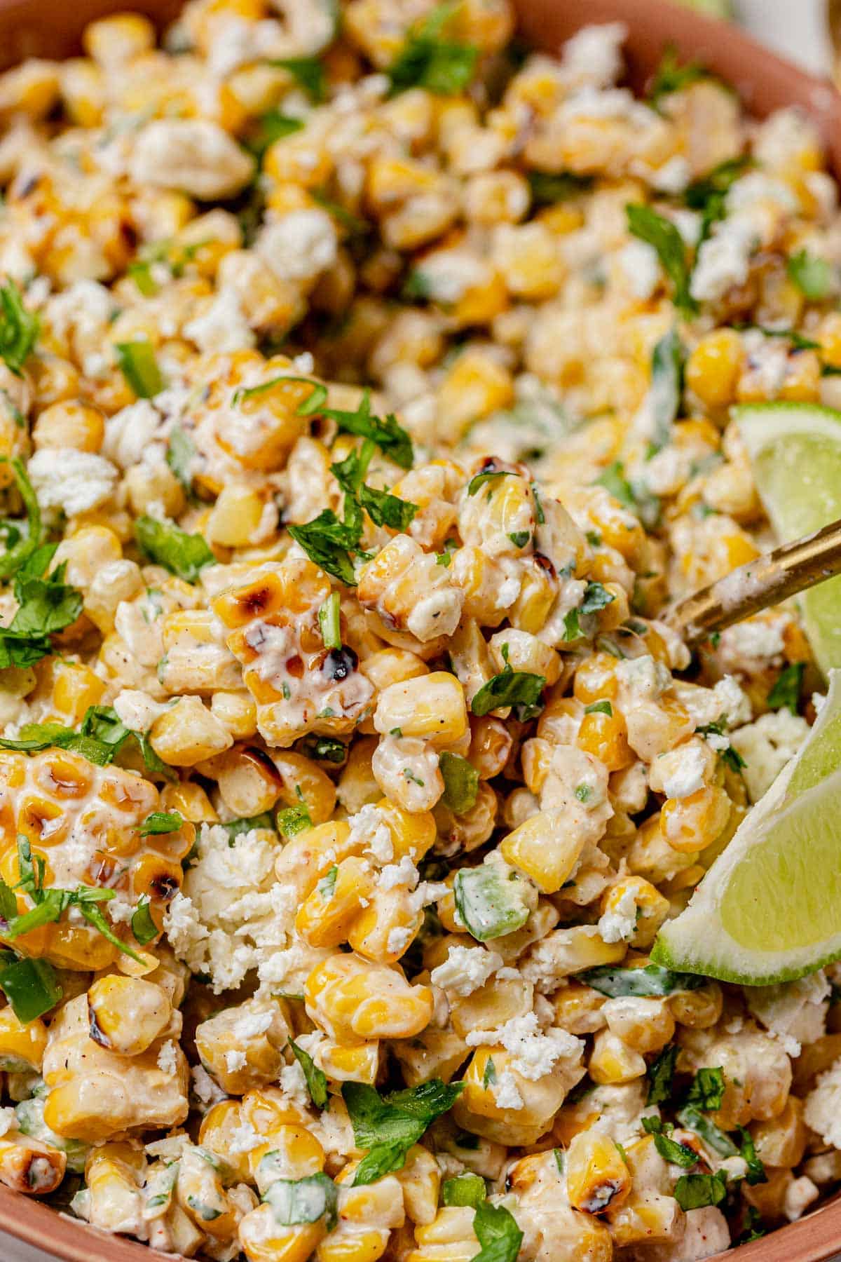 Mexican street corn salad showing creamy corn, herbs, cheese, and charred bits for texture and color.