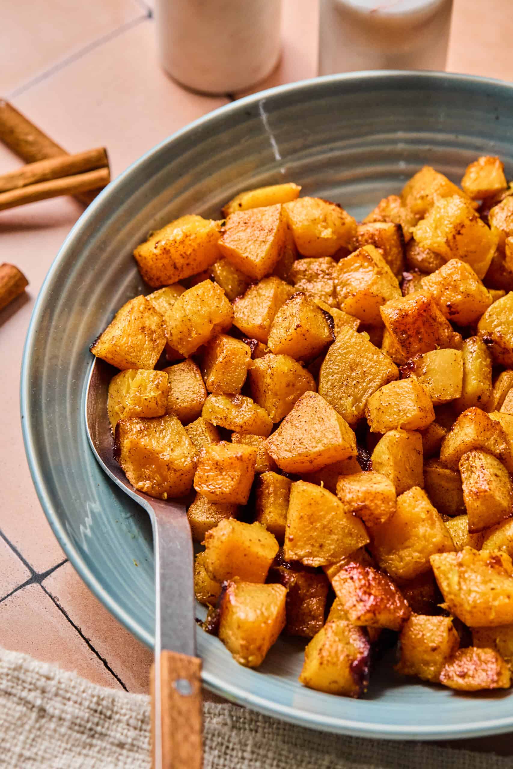 a spoon dug into roasted butternut squash cubes on a plate