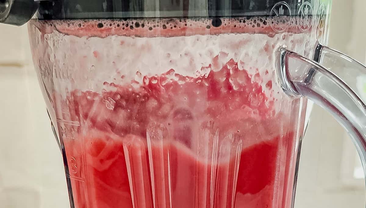 Watermelon being blended into juice in a clear blender for a watermelon vodka cocktail.