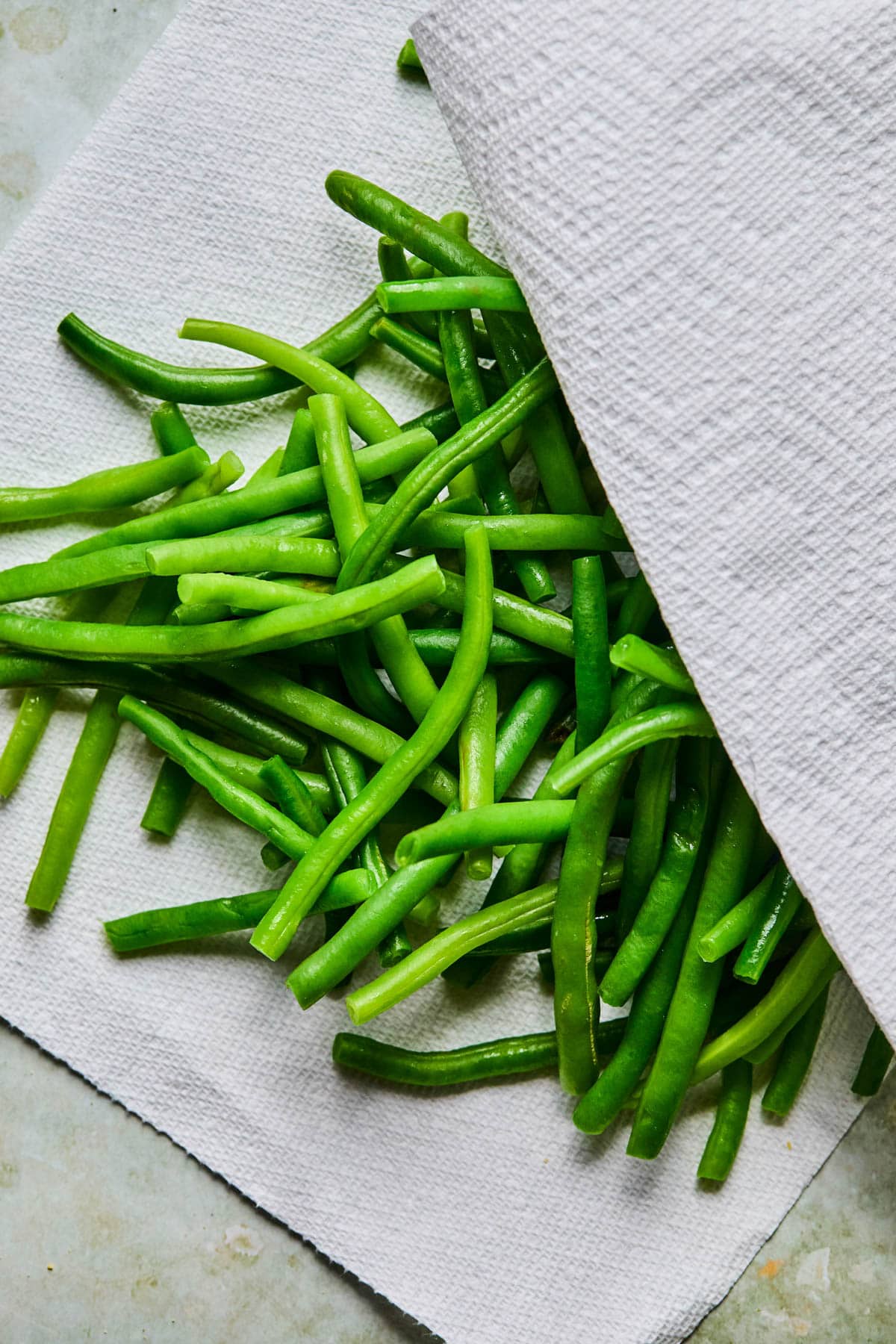 green beans being prepped and dried in a paper towel to make gluten-free dairy-free green bean casserole.