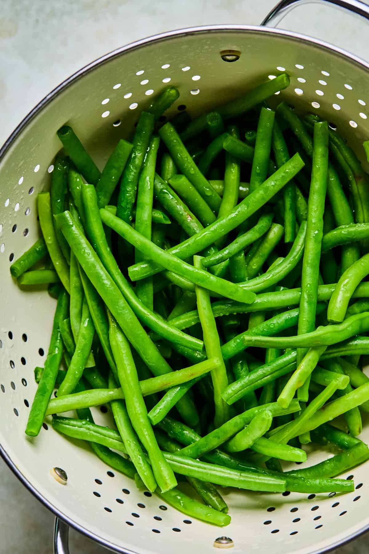 green beans being drained while prepping them for gluten-free dairy-free green bean casserole