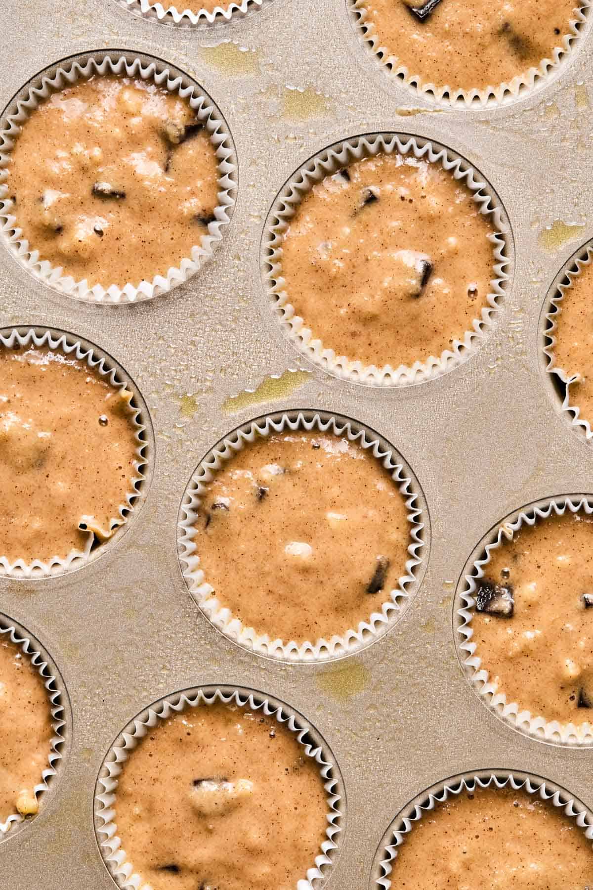 batter for almond flour banana muffins poured into a muffin tin lined with cupcake liners.