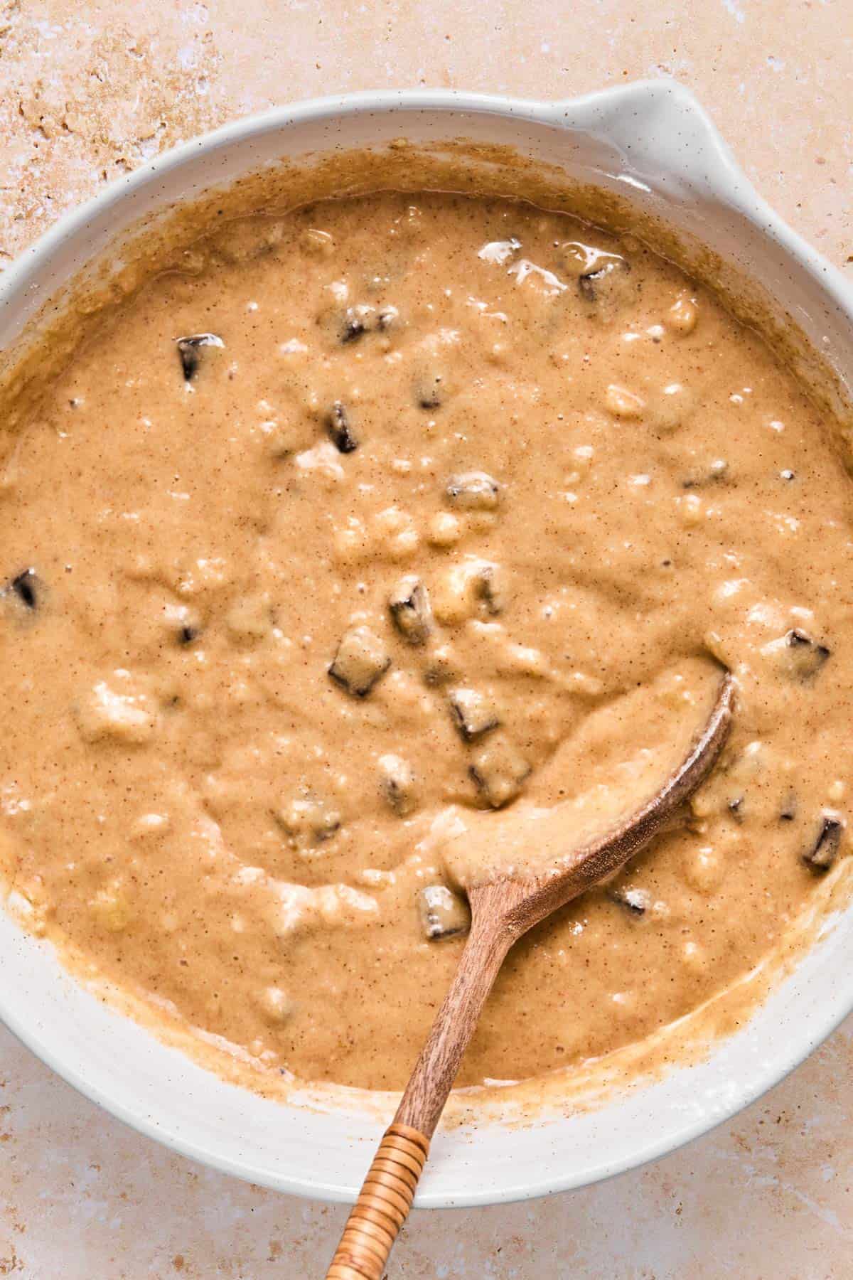 Mixing almond flour banana muffin batter in a large bowl with a wooden spoon.
