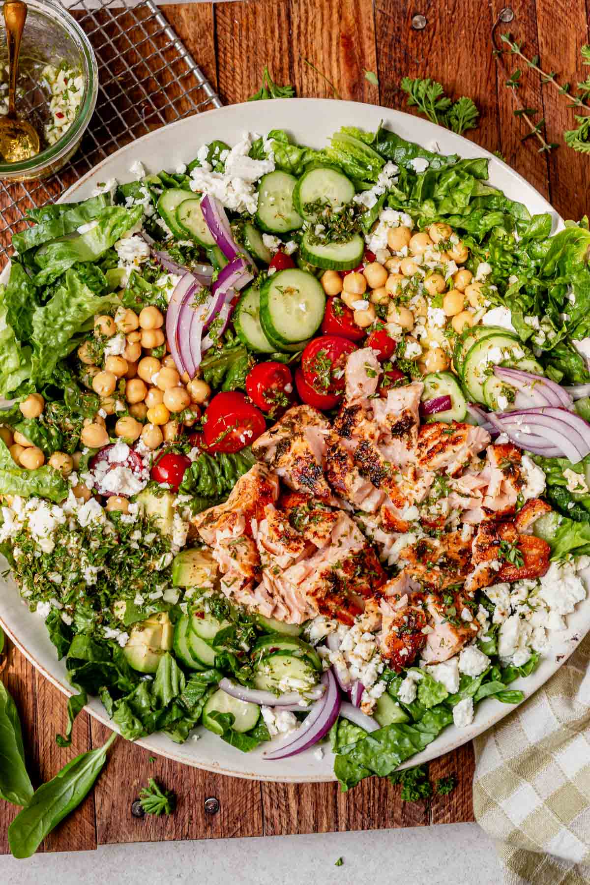 Salmon salad with salmon flaked into pieces over greens, cucumbers, tomatoes, and feta.