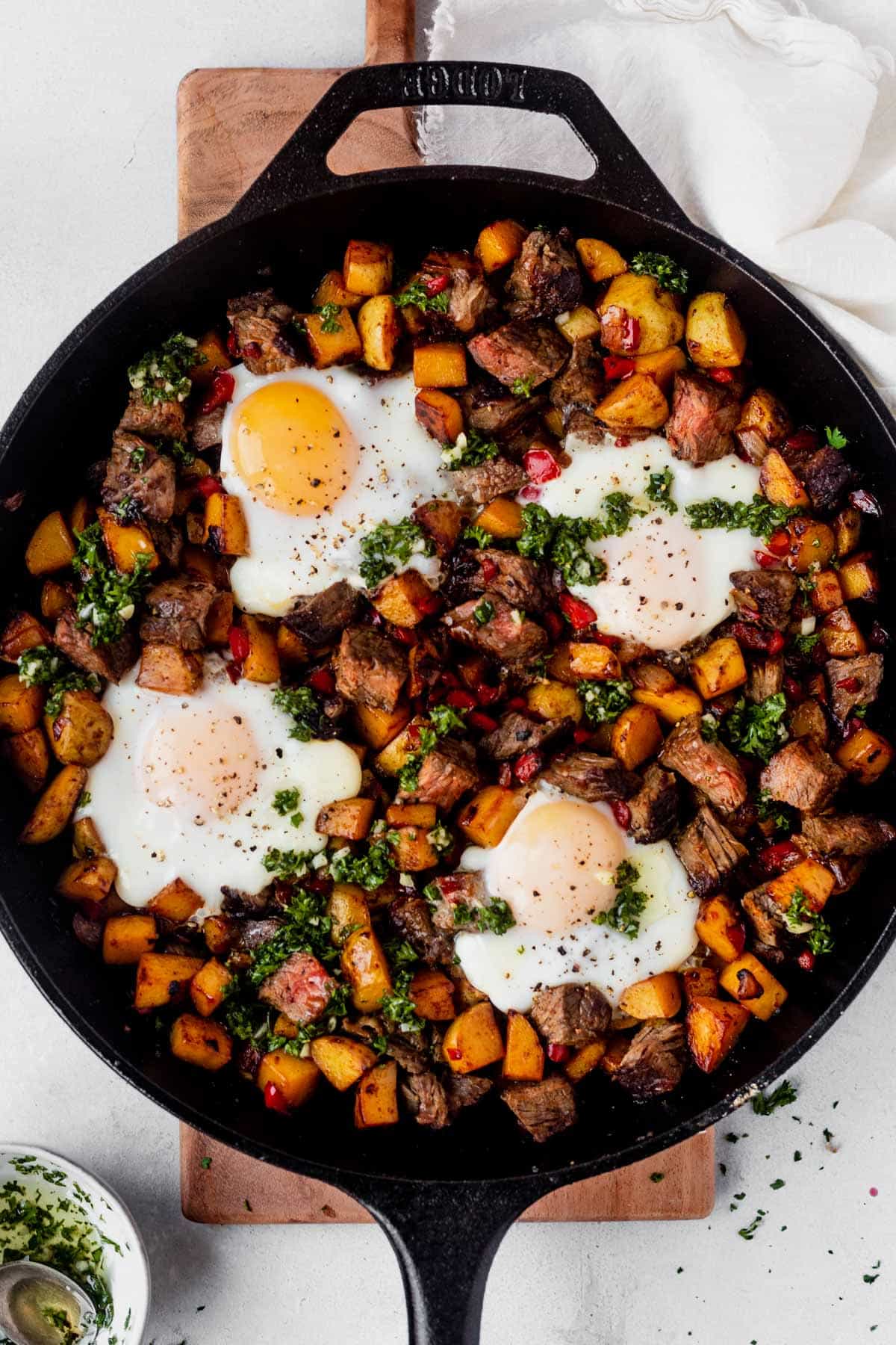 overeasy eggs overtop of hashbrowns and chimichurri in a skillet