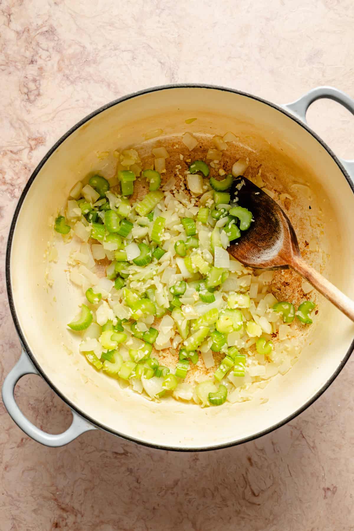 diced onions and celery simmering in a dutch oven to be used for easy vegetable soup.