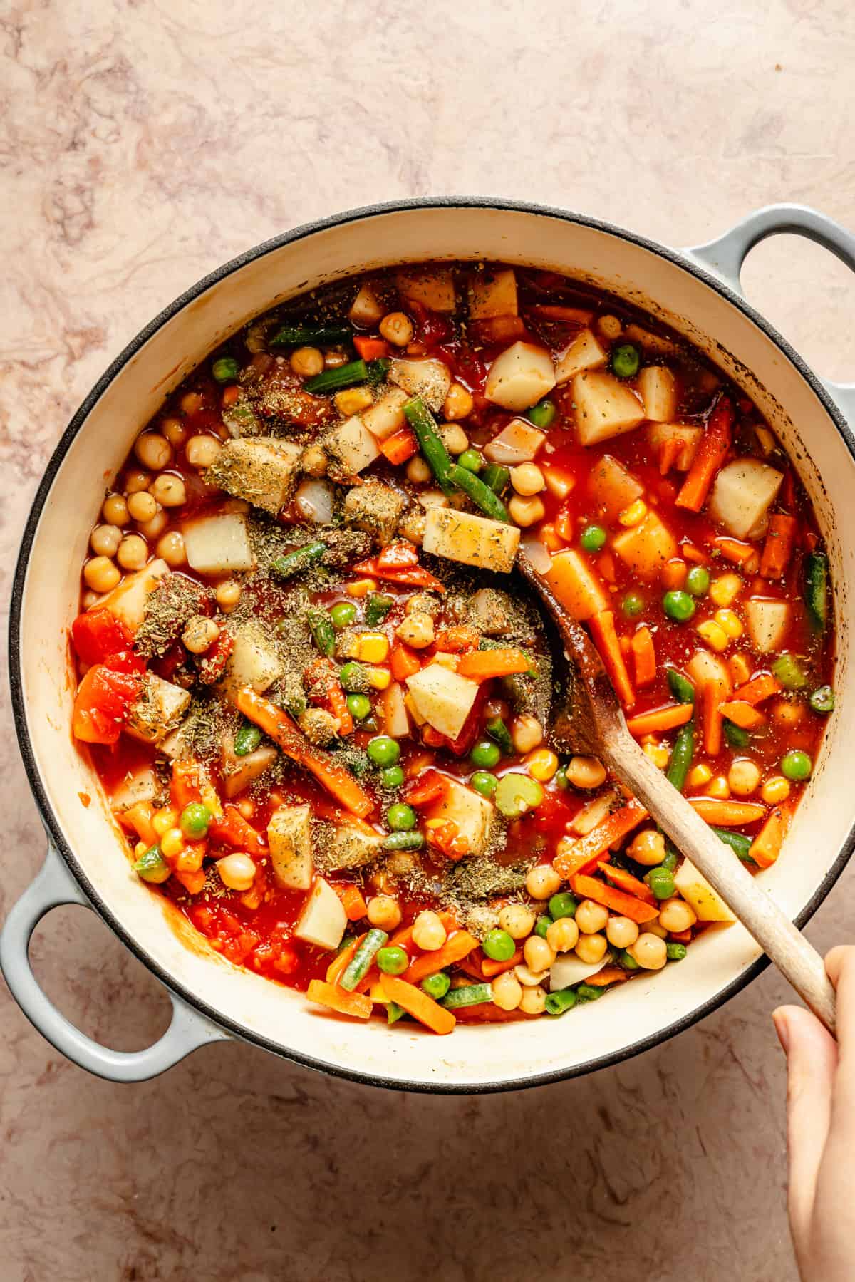 frozen vegetables, potatoes, tomatoes, tomato sauce added to easy vegetable soup crock with a ladle inside.