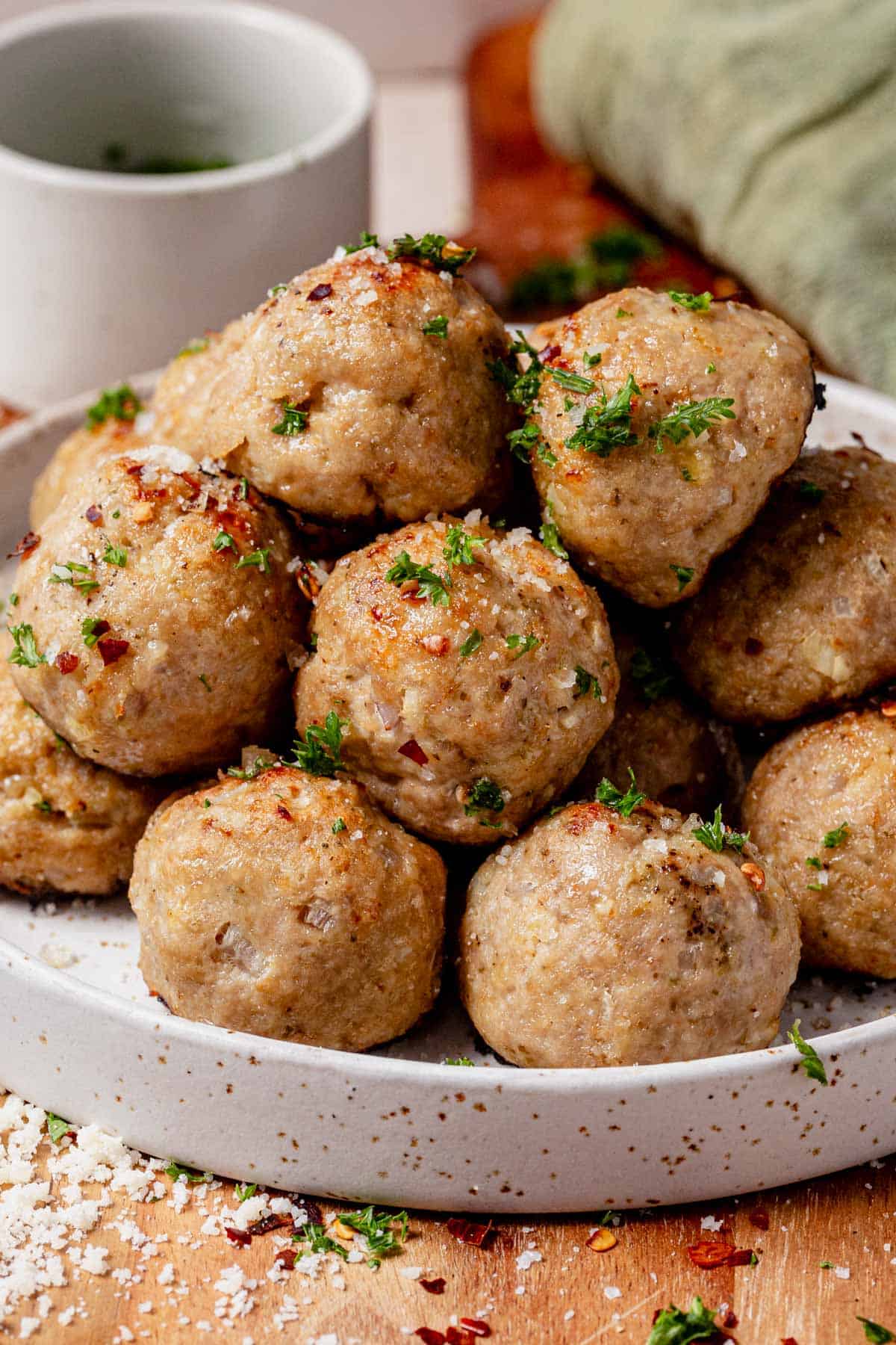 A plate of baked turkey meatballs topped with parmesan and parsley.