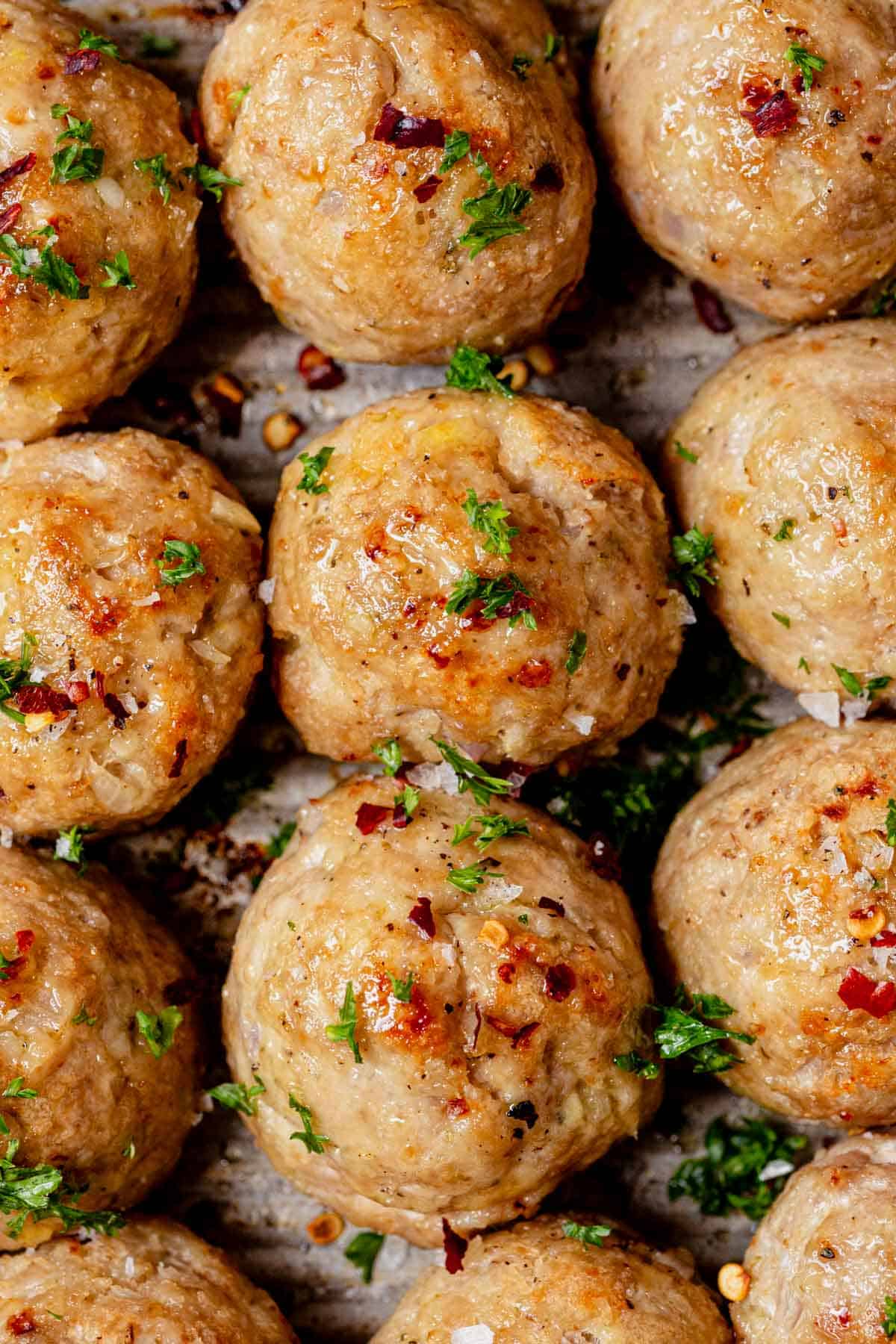 homemade baked turkey meatballs on a sheet pan with fresh parsley.