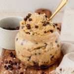 Close-up jar of creamy cottage cheese cookie dough with mini chocolate chips and a spoon.