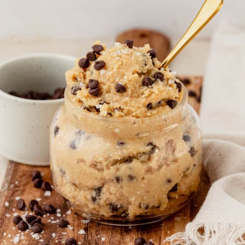Close-up jar of creamy cottage cheese cookie dough with mini chocolate chips and a spoon.