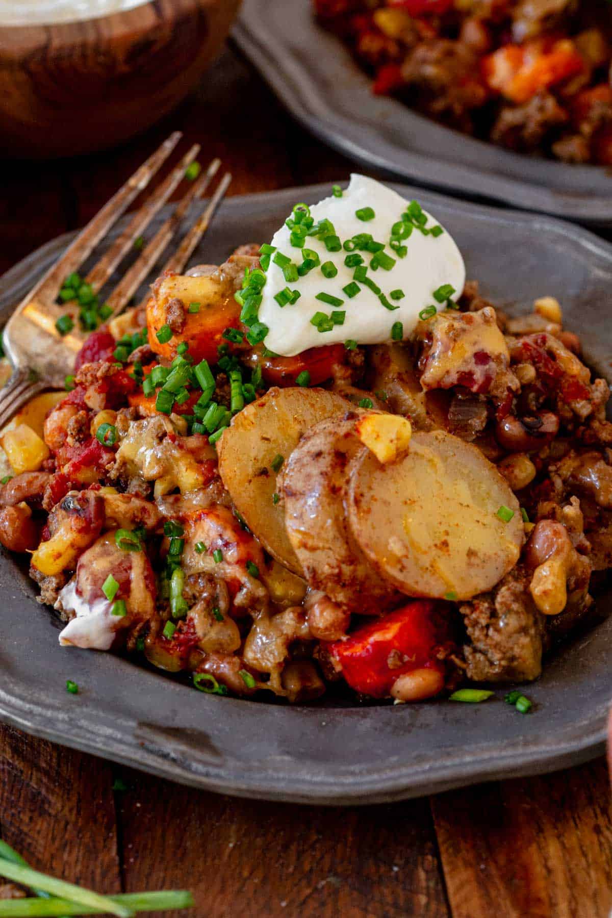 a plate of cowboy casserole with sour cream and melted cheese.