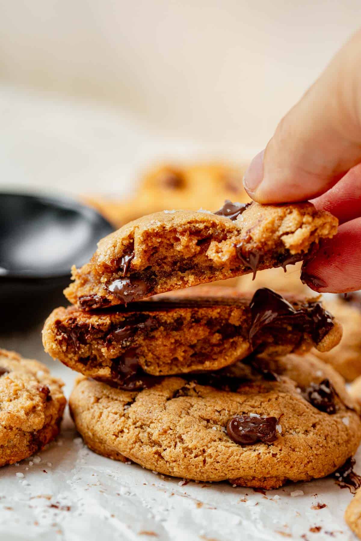 picking up a chocolate chip protein cookie from a stack.