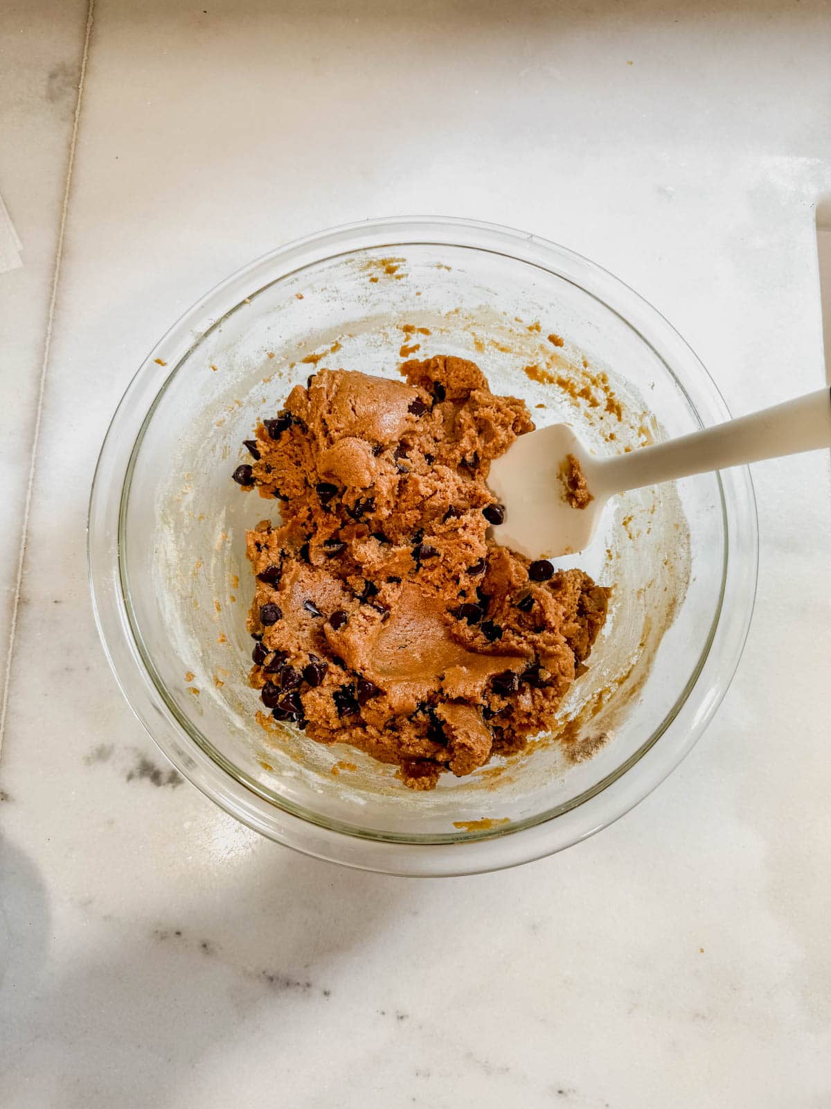 stirring chocolate chips into protein cookie dough.