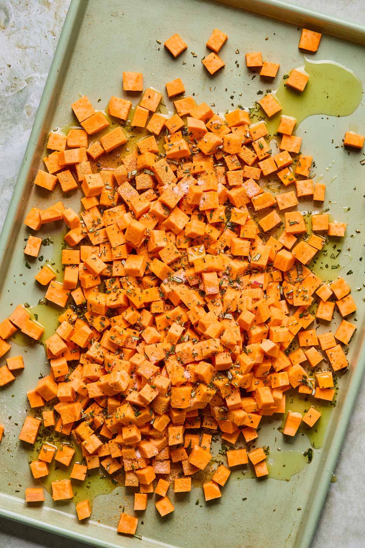 sweet potato cut up into chunks and laid out on a baking sheet.
