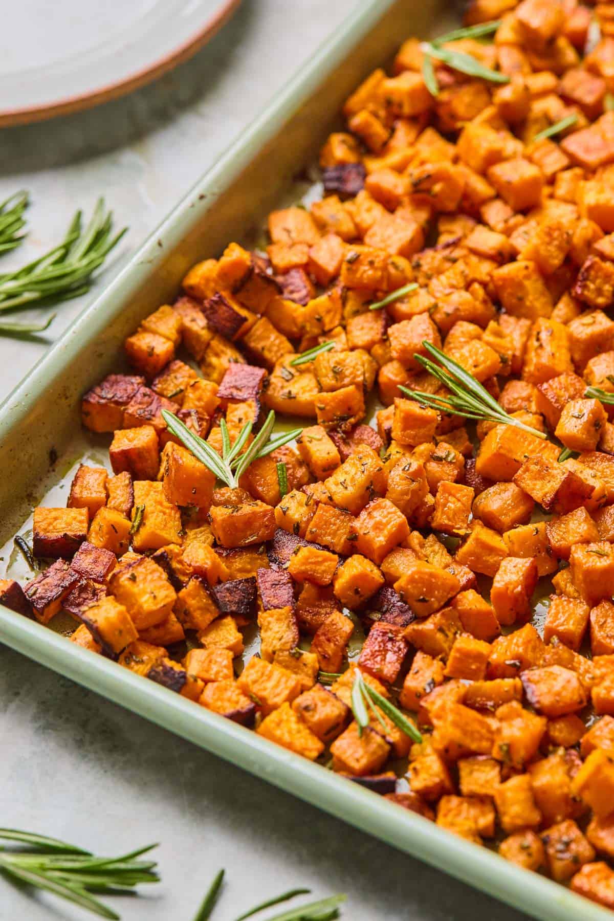baked rosemary sweet potatoes garnished with extra rosemary.