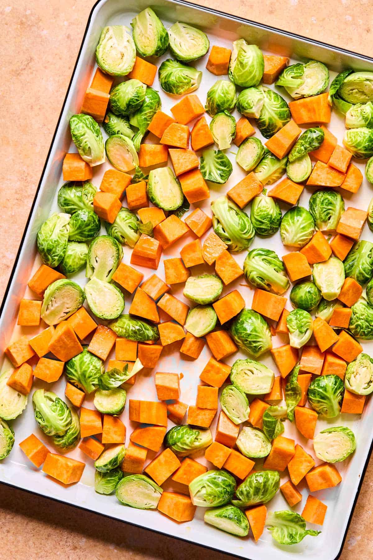 chopped burssels sprouts and sweet potatoes on a sheet pan.