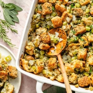 classic thanksgiving stuffing in a casserole dish with a wooden serving spoon.