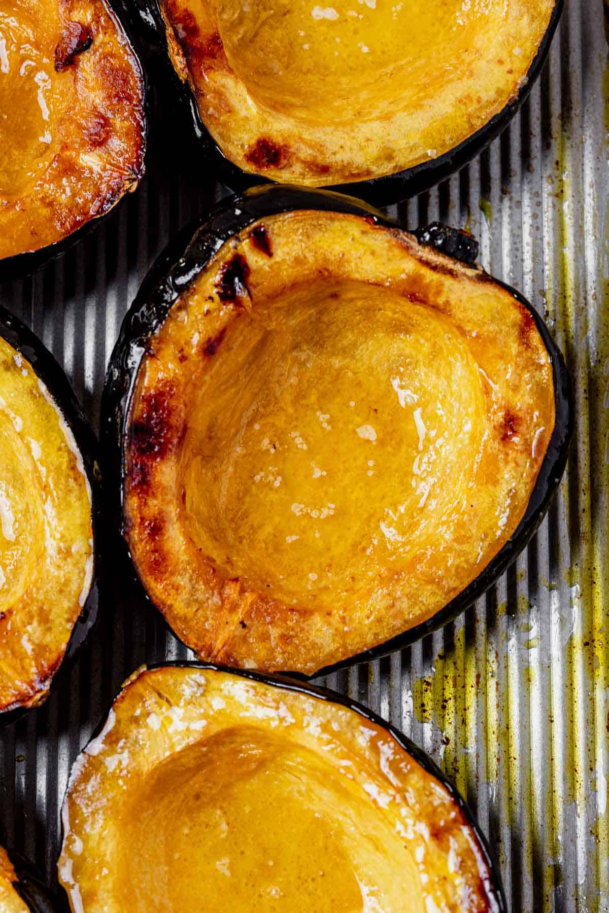 roasted acorn squash halves on a baking sheet with caramelized edges.