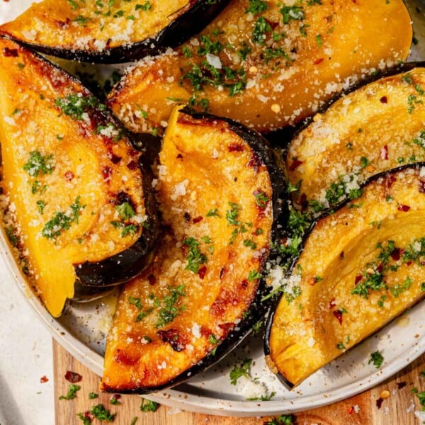 a plate of caramelized baked acorn squash topped with parmesan and parsley.