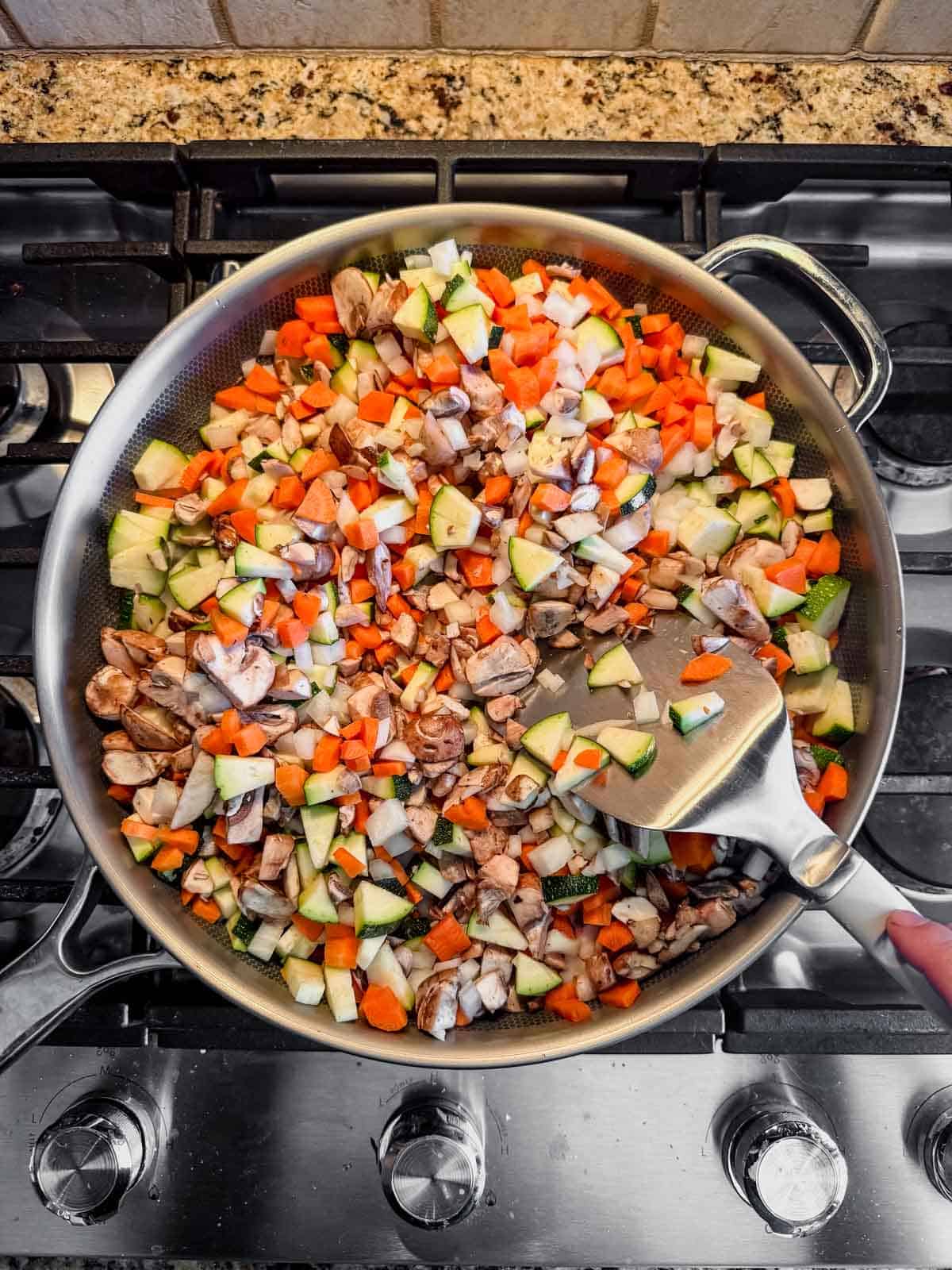 cooking chopped vegetables in a skillet for cottage cheese lasagna.