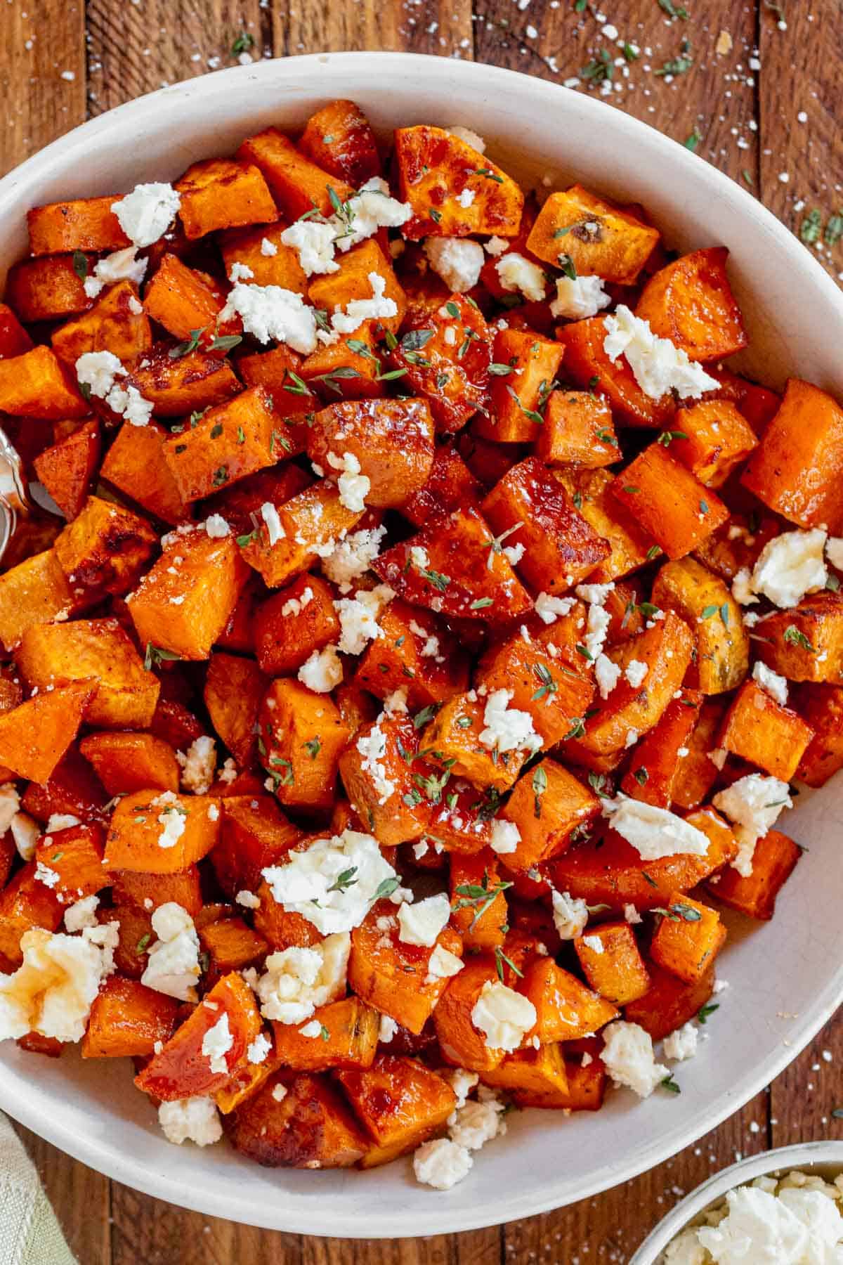 a bowl of honey roasted sweet potatoes drizzled with extra honey and thyme.