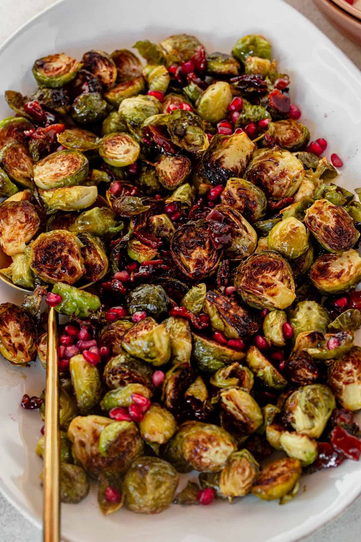 a platter of roasted brussels sprouts with maple and bacon with a serving spoon.