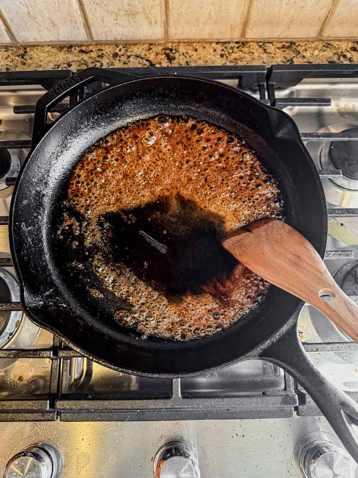maple syrup and bourbon glaze reducing in a skillet.