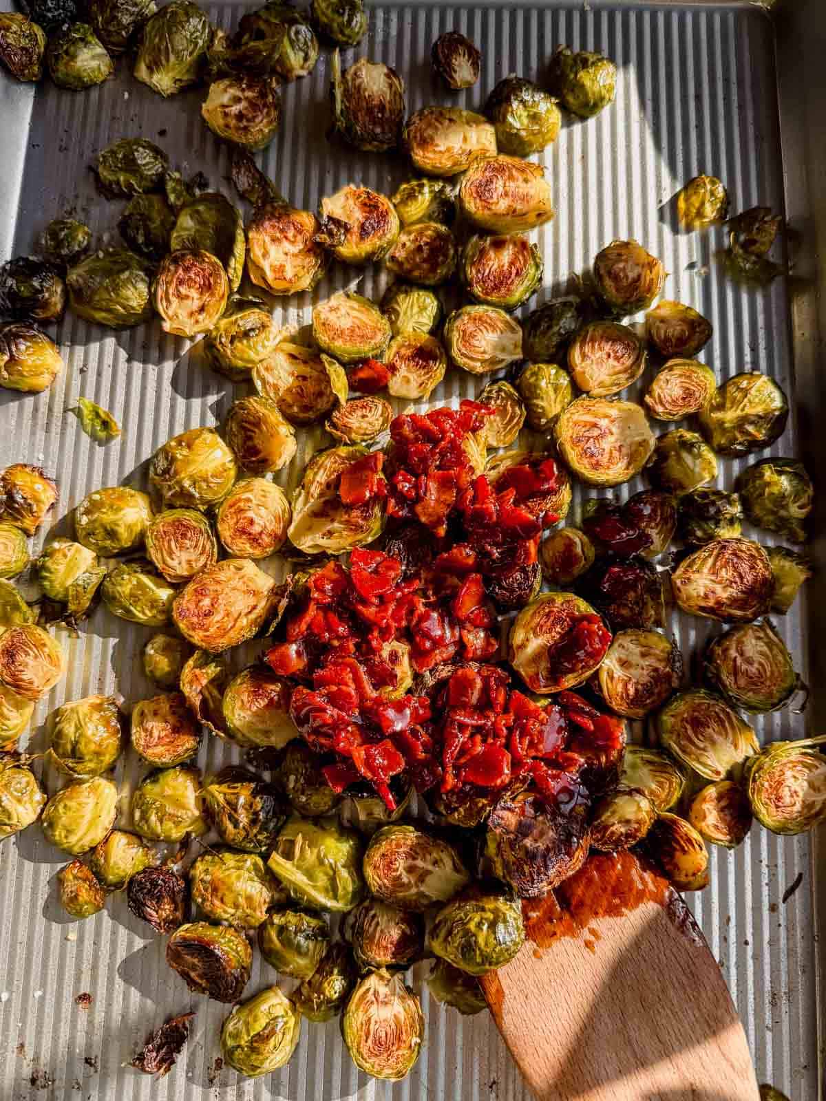 stirring roasted brussel sprouts with a maple bacon glaze.