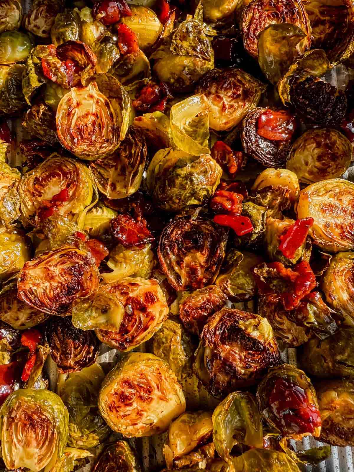 roasted maple bacon brussels sprouts tossed with the maple glaze on a baking sheet.